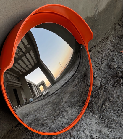 Convex mirror with orange frame on a construction site